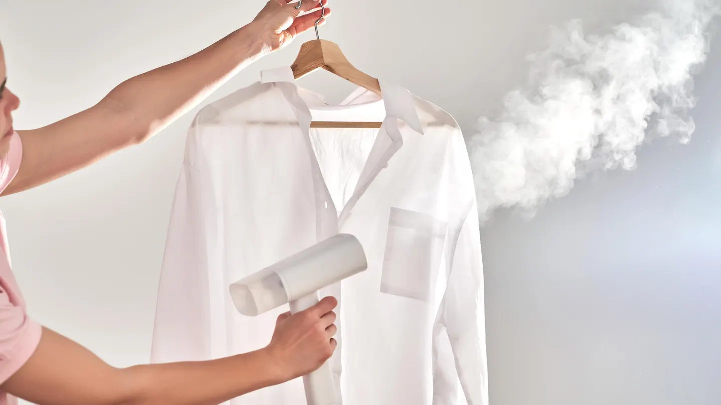 "Close-up of Hand Holding Clothes Steamer with Billowing Steam